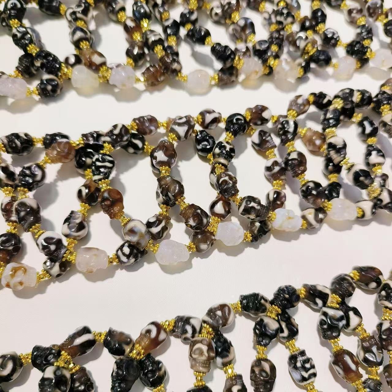 Multiple agate skull bracelets arranged on a clean light surface